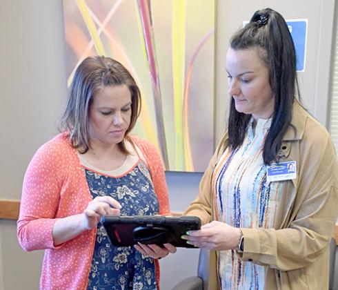 Memorial Health Clinic Manager Brandi Nigro, right, accesses MHC’s new online patient check in function with Head Receptionist Beca Hadenfeldt, using a tablet that is available at the clinic for those who don’t have a smart phone. 