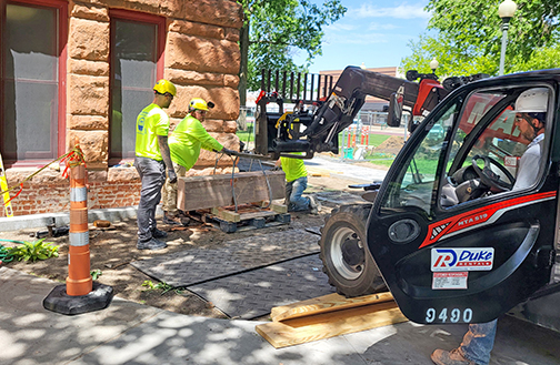 Stonemasons are working at the Hamilton County Courthouse to replace deteriorating sandstone blocks at the base of the 131-year-old structure. Above, a crew uses a small telehandler to replace one of the base stones near the building’s handicapped entrance. 