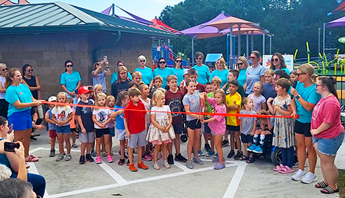 A group of children prepares to cut the ribbon signaling the opening of the Hamilton County Inclusive Playground.