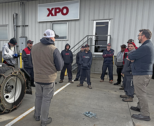 Safety training is on-going at the XPO service center in Aurora. Pictured here during a training exercise last November, driver trainer Lee Schuppan talks to drivers about when and how to apply snow chains.