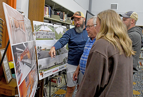 School board member Brandon Hunicutt (left) goes over diagrams of the project with community members Gene Consbruck (center) and Jordan and Jake Findley.