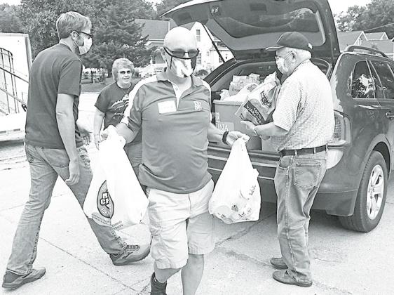 From left: John Christenson, Craig Shaffer and Chuck Anderson help unload bags and buckets filled with groceries during the Can Care-A-Van. News-Register/Jeni Moellenberndt