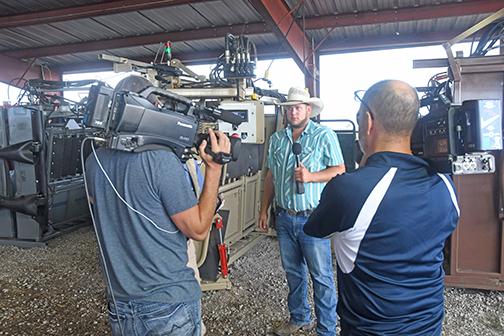 Austin Gubbels (center) runs through a description of the cattle chute he is demonstrating while multiple cameras record the process.