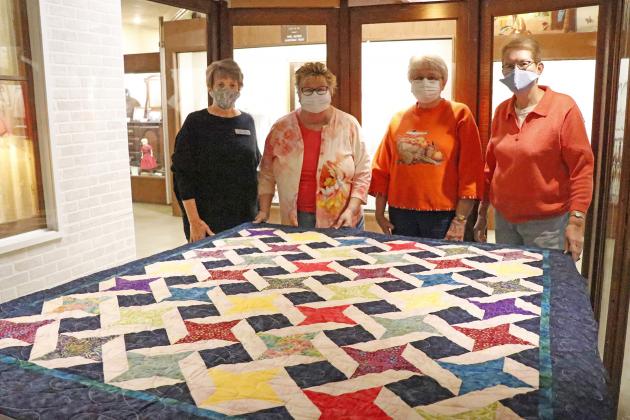 Plainsman Director Tina Larson (left) was on hand to receive this colorful, commemorative, friendship quilt from Nimble Thimble Quilt Guild members Sue Soper, JoEllen Ross and Claire Frevert. Not pictured is member Janice Wagner.