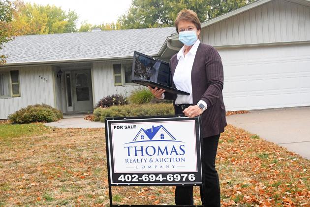 Laurie Pfeifer stands outside of one of the homes Thomas Realty & Auction has for sale. During the initial closures due to the pandemic, the local real estate firm utilized digital services to meet with clients and showcase houses.
