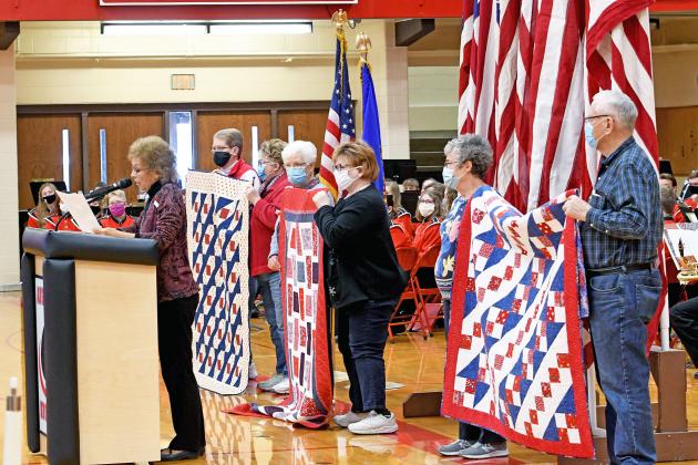 Members of the Thimble Nimble Quilt Guild help up their quilts for all to see. While they were not able to present them to the veterans during the ceremony, they were delivered afterwards.