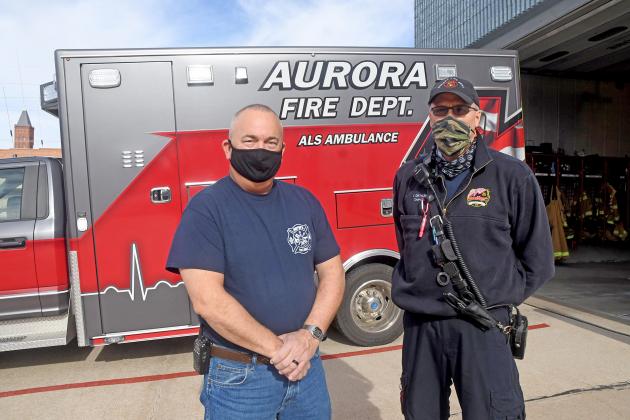Aurora Fire Chief Tom Cox, left, and EMS Captain Brent Dethlefs stand by one of the city’s four ambulances, used as part of the new fire-based emergency medical service.