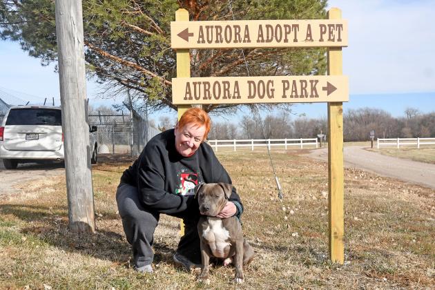 New shelter manager, Sandy Summers, stands next to the Aurora Adopt A Pet sign with one of their dogs that is searching for their forever home.