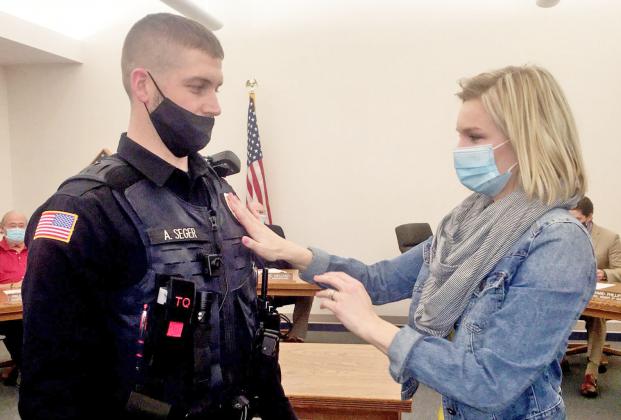 Grayce Seger pins an Aurora Police Department badge on her husband, Adam, after he was sworn in Jan. 12 as a new member of the APD.