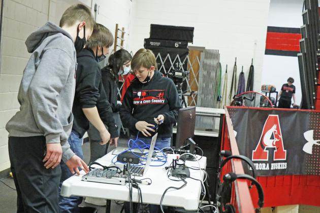 Media Productions students Cole Krejci (left), Danny Slocum and Spencer Griess help set up components of the Striv broadcast as well as the Daktronics scoreboard system. 