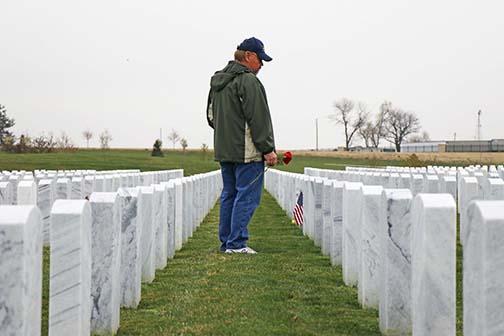 Navy veteran Aaron Nilson takes his time at the Omaha National Cemetery, waiting for the perfect headstone to place his red “Rembrence Rose.”