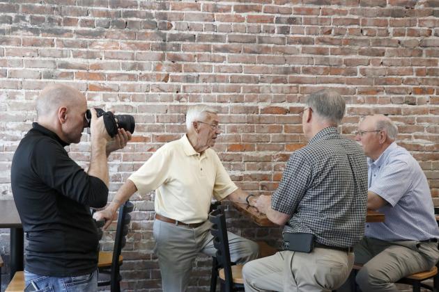 Brian Kreikemeier, left, films people interacting at Maker’s, which provided one of the closing scenes in a video recognizing the city’s 150th anniversary. Pictured from left are Jim Koepke, Marlin Seeman and Rick Melcher.