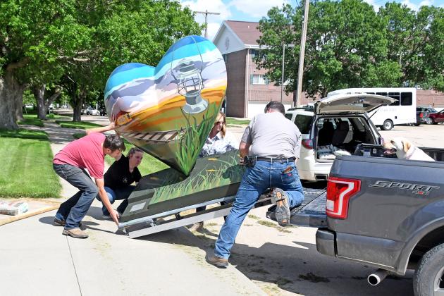 Brennan Emahizer (left), Jennifer Emahizer, Tammy Morris and Trevor Emahizer work to unload the updated heart statue and place it back in front of the Alice M. Farr Library.