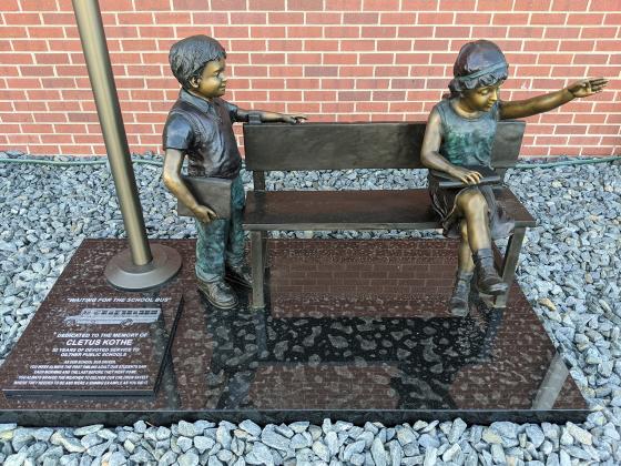 The statue “Waiting for the Bus” and flag pole were given in memory of Cletus Kothe by his family. Kothe drove bus for the Giltner school for 52 years and passed away in 2020.