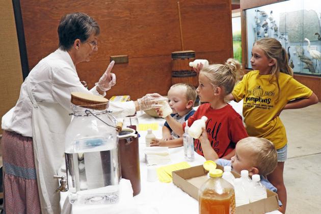 A fan-favorite at Day on the Farm, the Mickey children (right) learn the basics of making butter from Marcia Spiehs.