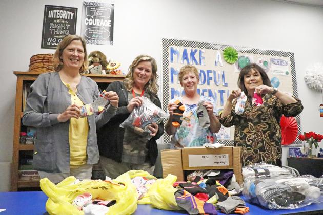 The donation of 150 pairs of socks to Hamilton County was well received by Aurora school nurse Sharon Christensen (left) and counselor Erlinda Amen. Delivering the socks were Colleen O’Neill, vice president and Cheryl Schuett, treasurer of Gamma chapter of Delta Kappa Gamma. 