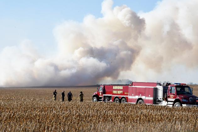 Aurora firefighters look on in a corn field near Marquette where fire spread quickly Oct. 19, burning an estimated 30-40 acres before it was contained.