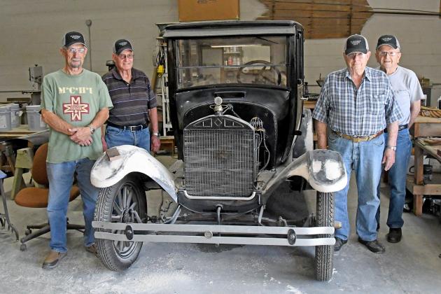 From left, Dale Saddler, Don Bish, Gary Bayne and Walt Jacobs stand together by their current project at the Plainsman Museum. This group of volunteers has been working on restoring vintage vehicles for the museum.