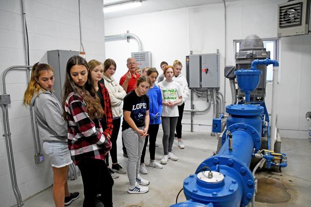 Mayor Marlin Seeman (back, center) show students how the pumping systems pulls groundwater up and then how it delivers it to homes.