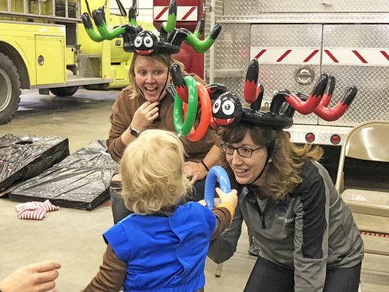 Angie Arndt, left, and Margo LaBrie were all smiles as young Kaius Parsley tried to throw a ring onto LaBrie’s antler hat, all part of the Hampton Trunk or Treat event Sunday at the fire barn.