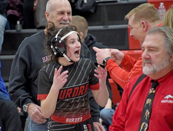 Aurora’s Natalie Bisbee was almost in shock after winning her third place match and officially punching a ticket to the first-ever NSAA girls state wrestling tournament, sharing this moment with coach Derek Keasling.