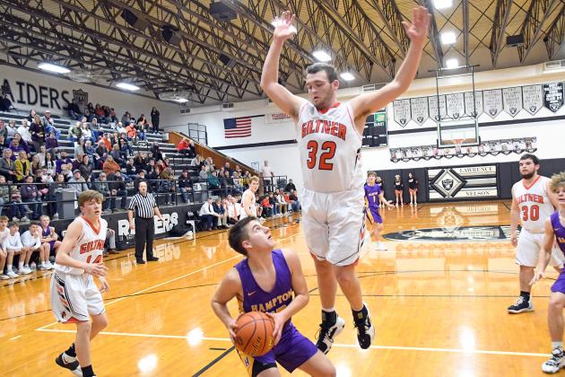 Giltner’s Jacob Smith takes flight in defense as Hampton’s Tyson Wolinksi looks for a bucket in the paint during the  Hornets’ 45-44 win over the Hawks in the D2-3 subdistrict tournament played at Lawrence-Nelson Feb. 22. 