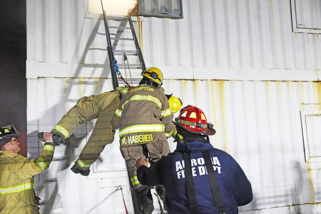 Hampton firefighter Matt Haberer receives help from Aurora firefighters Bobby Meade (left) and Clinton Roberts (right center) while carrying Tanner Greenough down the ladder during a two-person rescue.