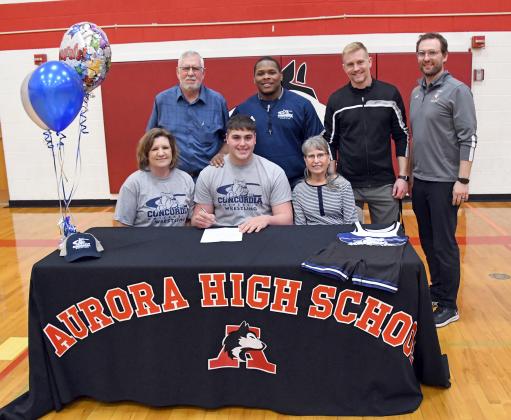 Aurora senior Aaron Jividen signed his letter of intent last week to wrestle for the Concordia Bulldogs. Joining him at the March 29 signing ceremony were, front from left: his mother Ronda Jividen and grandmother Theoramae Ortegren. Back row: Grandfather Darold Ortegren, acting Concordia wrestling coach Tyree Cox, and Aurora wrestling coaches Derek Keasling and Brandon Timm.