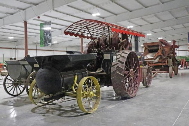 This large and in-charge piece is a steam engine, used in place of a tractor, to pull a thresher machine through a field.