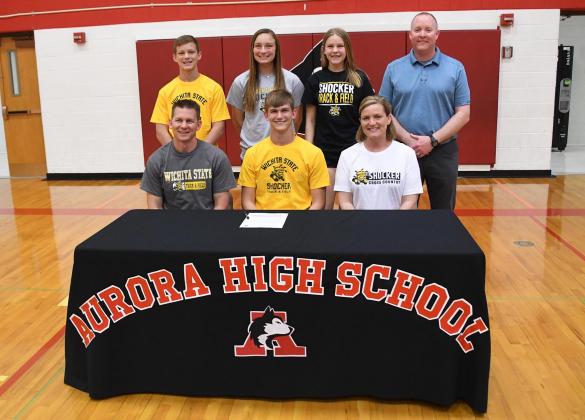 Aurora senior Caden Carlson, front center, signed his letter of intent April 22 to continue his pole vaulting career at Wichita State University. Pictured with him are, front row: parents Chad and Yvonne Carlson. Back from left: siblings Ryan, Kyla and Jenna Carlson, as well as head track coach Gordon Wilson.