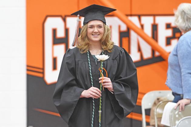 Macie Antle walks down the aisle in the Giltner High School gymnasium holding a white cremone, the Class of 2022 flower.