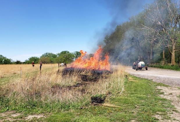 Crew members monitor a control burn conducted in May near the entrance to the Prairie Plains Resource Institute warehouse and education center northwest of Marquette.