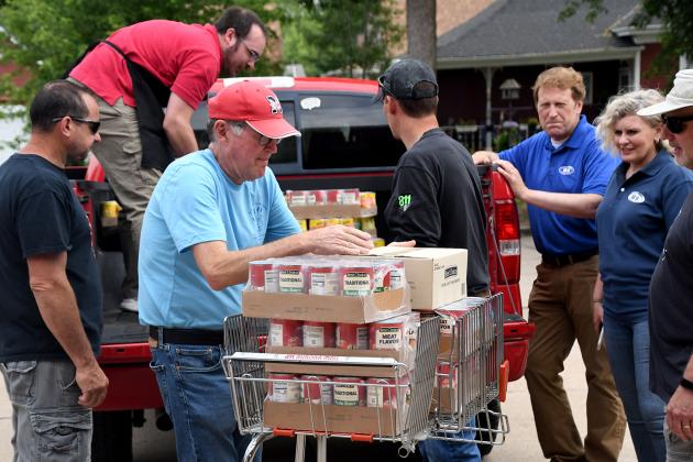 Food pantry board member Bruce Ramsour, front center, helps unload a delivery during last week’s Can Care-a-Van drive. Pictured at right are Channel 10/11 representatives Jon and Taryn Vanderford.