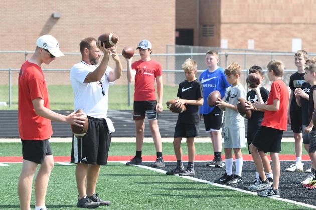 From left, Husky QB Drew Knust and Coach Kyle Peterson demonstrate how to properly grip a football during the first-ever Youth Quarterback Academy coordinated last week by the Edgerton Explorit Center.