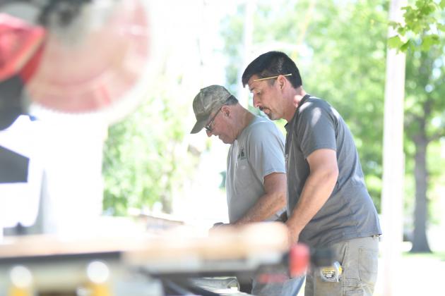 Ryan (right) and Eugene Bamesberger work on a piece of wood that will soon be sawed into measured  into planks. Materials like wood, concrete, latex, paint, windows and doors consistently are delayed for often months at a time.