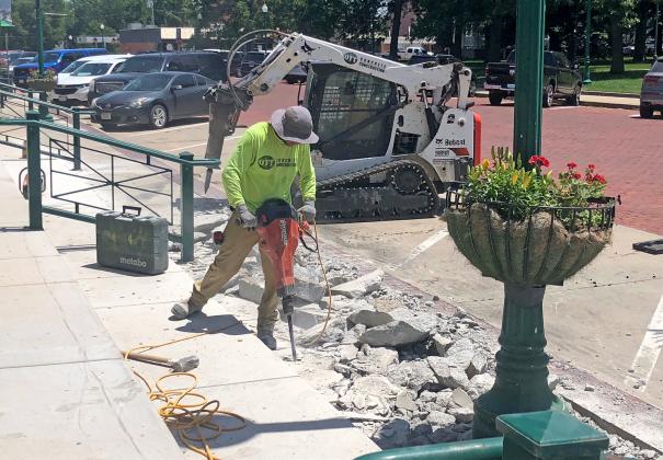 Workers with Ott Concrete Construction use their electric jackhammers to peel away the old concrete sidewalk for a new one to be put in on the north side of downtown square. 