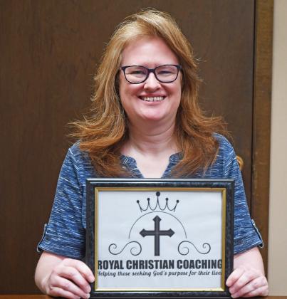 Julie Dudley holds up the logo for her business, Royal Christian Coaching. Dudley is life coach who said she uses Christian practices to help people reach their goals.