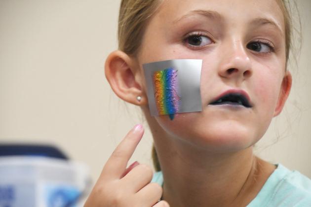 Sydney Hansen gets a rainbow colored Pegasus face painting from Kim Evans.