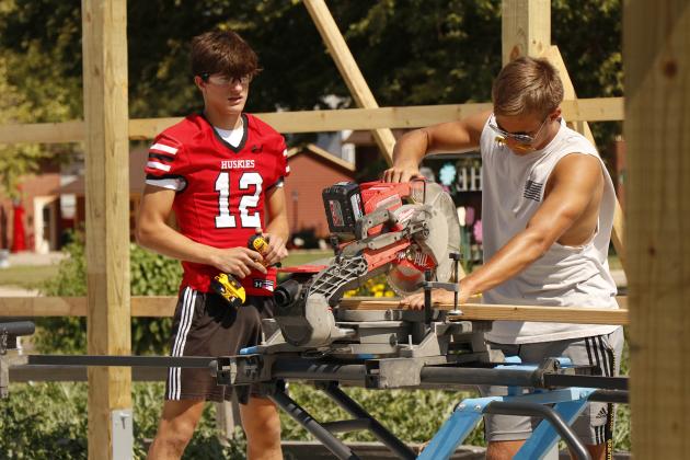Students Devin Otto (left) and Connor Smith work to cut a board to the right size for a piece of the ag building’s frame.