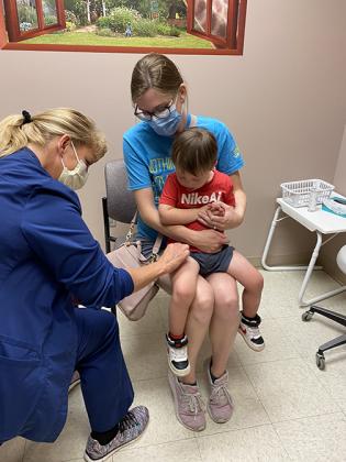 Jennifer Heiden holds her son Creed as Memorial Health Clinic nurse Deana VanDeWalle administers a first dose of the approved COVID-19 vaccine for children age six months to 4 years.
