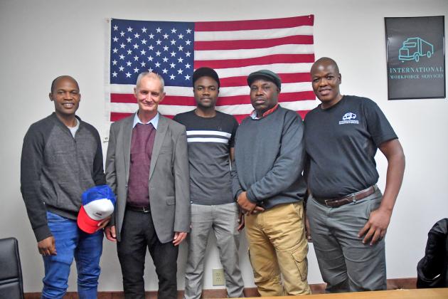 Pictured from left are International Workforce Services clients including James Mashumba, Mark White, Marshal Kadziri, Lancelot Masangudza and Nevson Zisusa. White is from South Africa, while the others are all from Zimbabwe. The IWS truck driving logo is pictured top right.