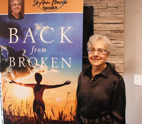 Author JoAnn Marie poses next to her promotional board at her home in Aurora. In the book, “Back from Broken: A Journey of Healing from Victim to Victor,” Marie details her sexual abuse as a child and how her faith and counseling helped her heal from the trauma.