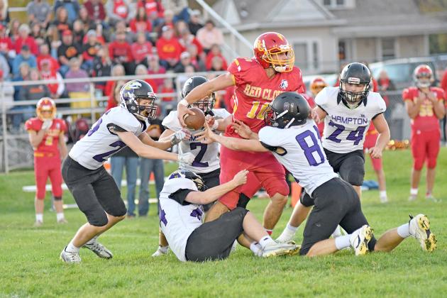 Hampton’s defense swarms Red Cloud’s Ben Ely as he looks for a receiver downfield with five of the six visiting players in frame during the Hawks’ 60-14 loss to the Warriors. 