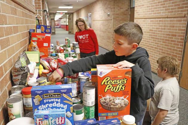 Working hard to get donations ready for their trip to the food pantry after a week of collecting, Aurora fifth graders Josiah Peterson (center) and Cody Rinke (far right) spent time choosing the perfect items to balance out boxes. Parent volunteers like Kim Eberly also assisted, including helping to transport goods to their end destination.