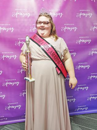 Kadee Luebbe wears her pink dress, complete with the sash and trophy she won as Junior Teen Queen from the Miss Amazing competition Oct. 29.