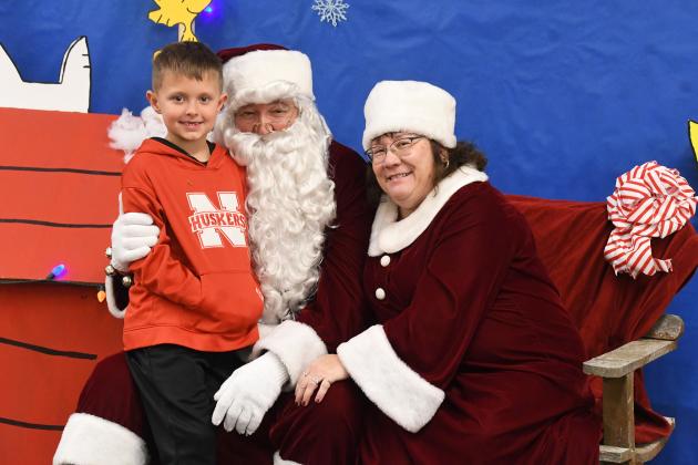 Kyson Peterson poses a picture with a couple known as Santa and Mrs. Claus. Santa remarked that the event was up to his standards.