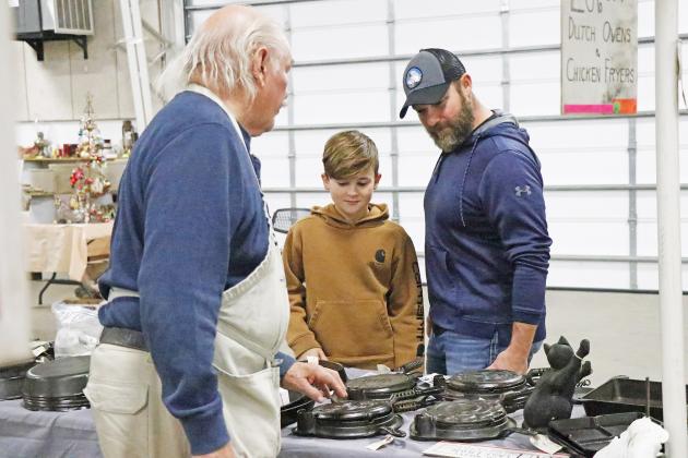 “The Cast Iron Guy” Thomas Hamilton (left) explains the story behind some of his antique wears to Oliver Rose and Kyle Peterson at the Craft, Toy and Gun Show Dec. 4 at the Hamilton County Fairgrounds.