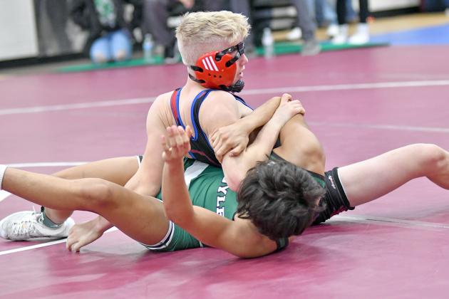 HPC’s Gage Friesen rolls over to his back and still gets the pinfall while his vision was blocked by his headgear during Friday action at the Norm Manstedt Invitational. 