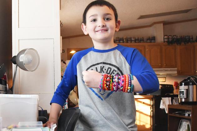 Rilee Jemison shows off bracelets and beads that he made himself at his workstation in his home in Giltner. Jemison has been making crafts by watching YouTube videos with help from his mother.