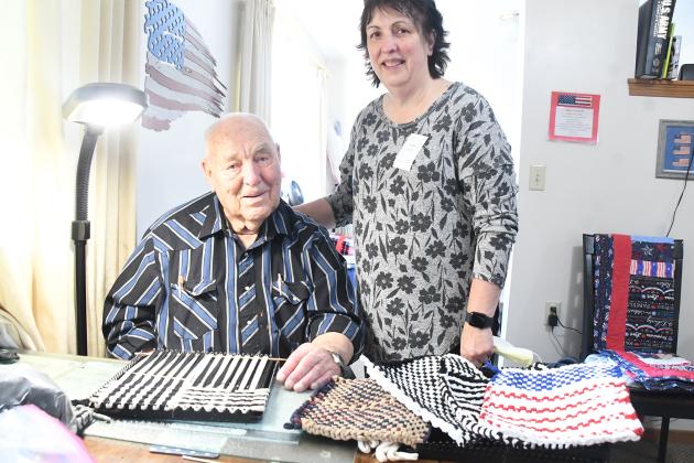 Ramer Fassnacht with his daughter Teresa Elder-Smith and completed hot pad holders, with one in progress, on the table at his apartment in East Park Villa. Fassnacht makes up to 20 a week and his daughter helps finish them and works with her two sisters to sell his creations.
